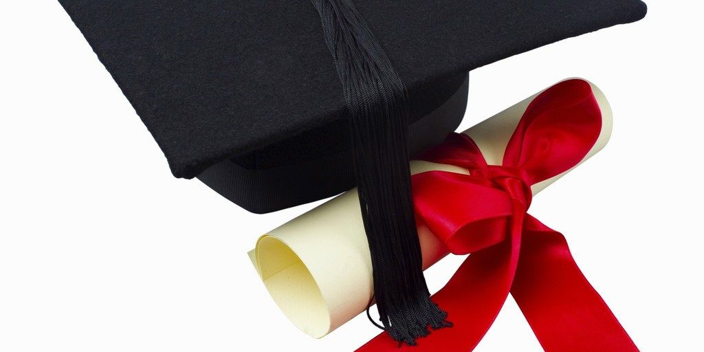 Close up of a graduation cap and a certificate with a ribbon
